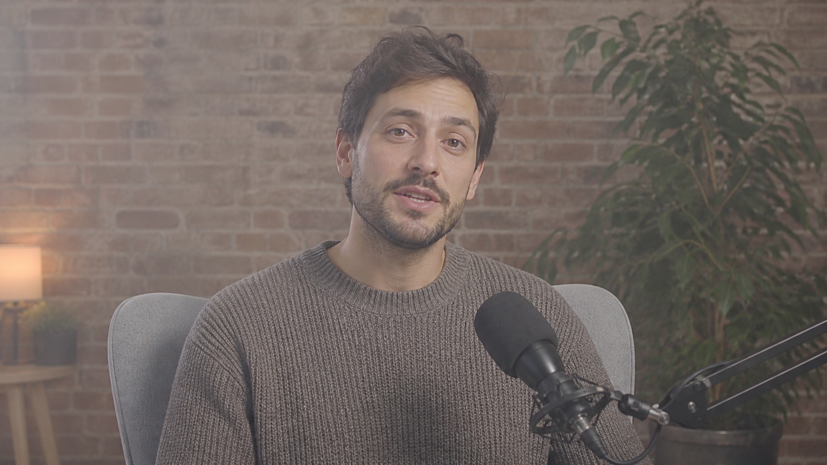 A soft hazy creator video with visible hair, knitwear, brick, leaves and a microphone